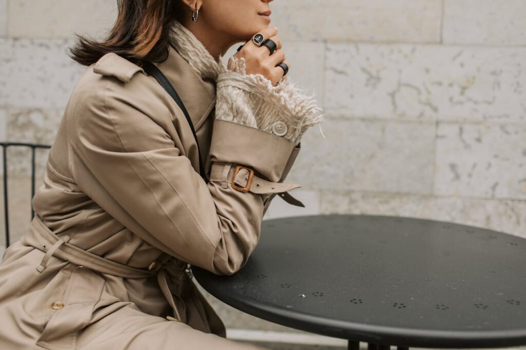 Woman Wearing Trench Coat Sitting at a Table
