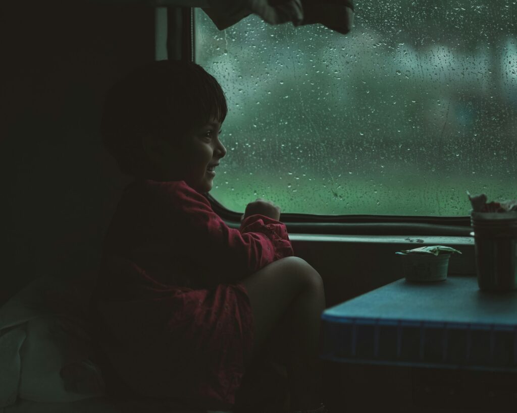 a child sitting on a window sill
