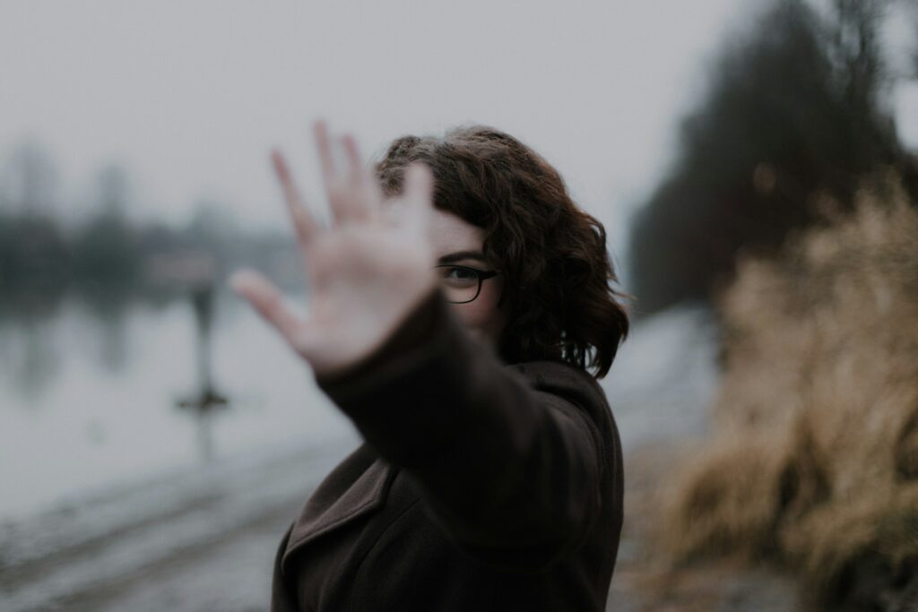 woman in black coat standing near body of water during daytime
