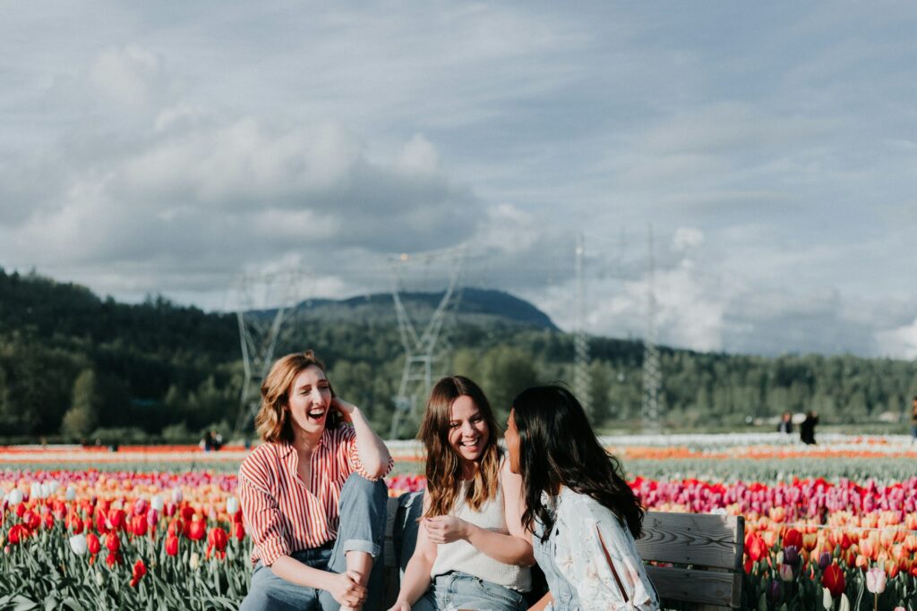 3 women sitting on bench near the flowers
