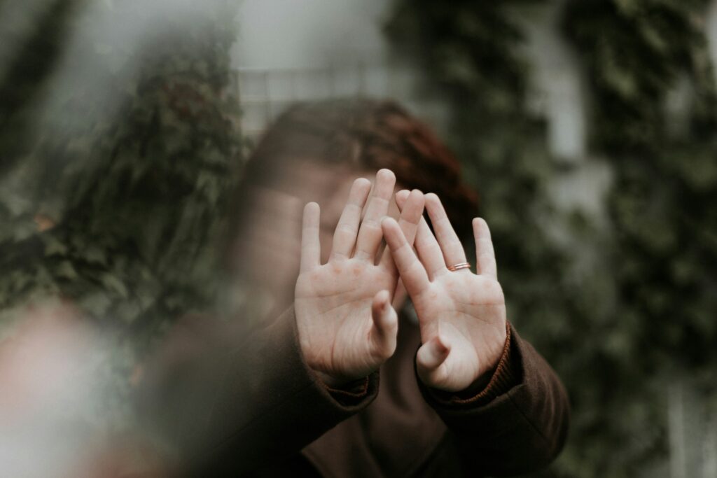 person in brown long sleeve shirt covering face with hand
