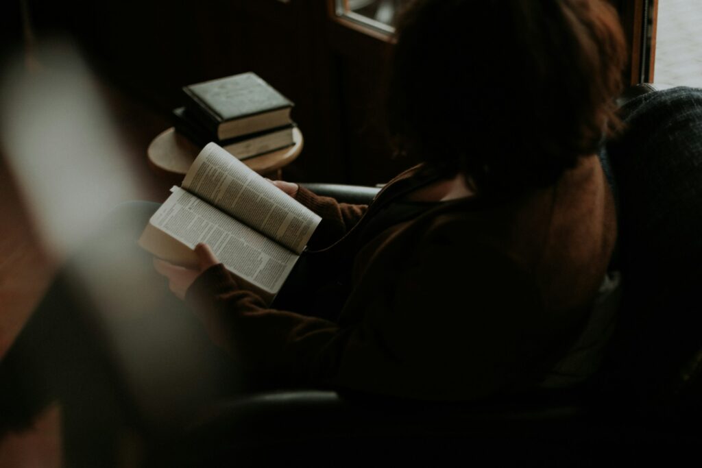 woman reading book on sofa