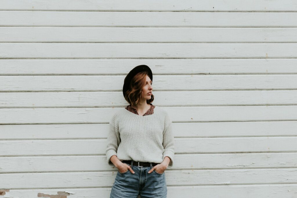 woman leaning on wall wearing gray sweater

