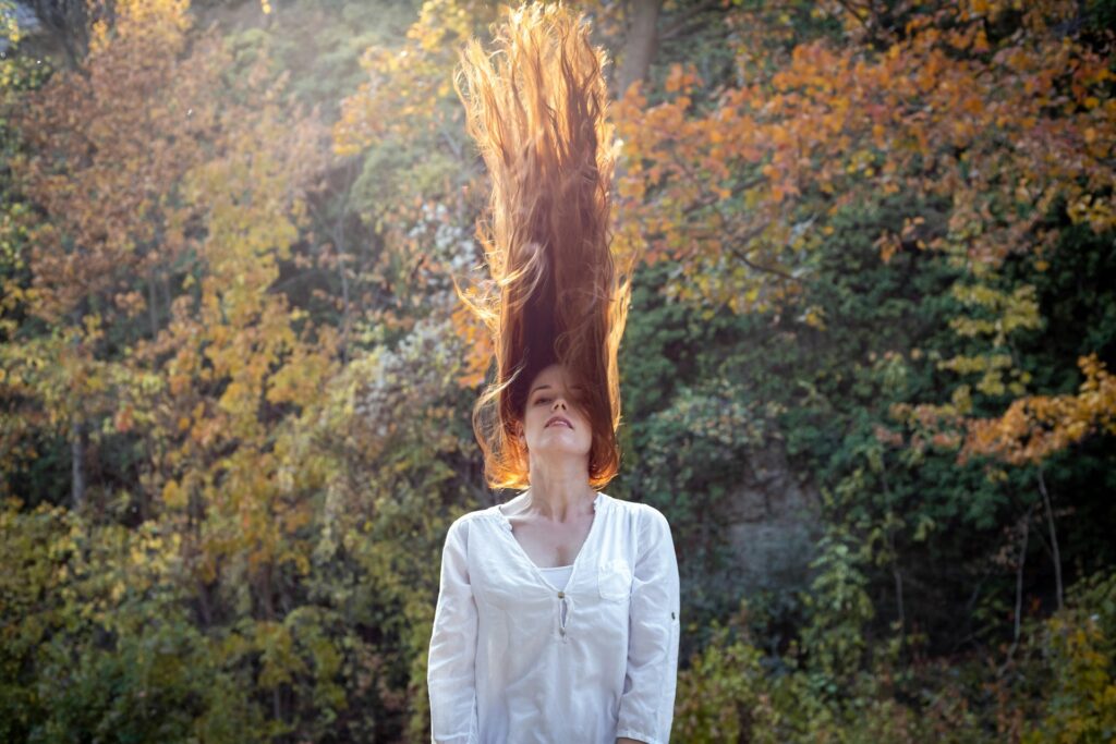 woman wearing white long-sleeved blouse while hair is going upward
