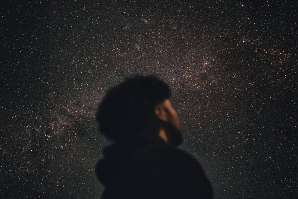 A man standing in the dark looking up at the stars
