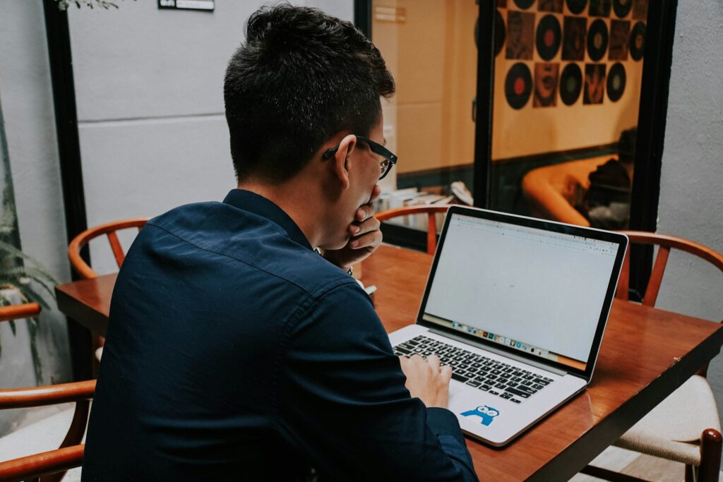 a man sitting at a table using a laptop computer
