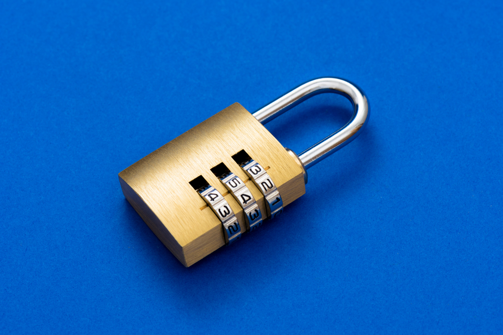 Close-up combination golden padlock on the blue background.
