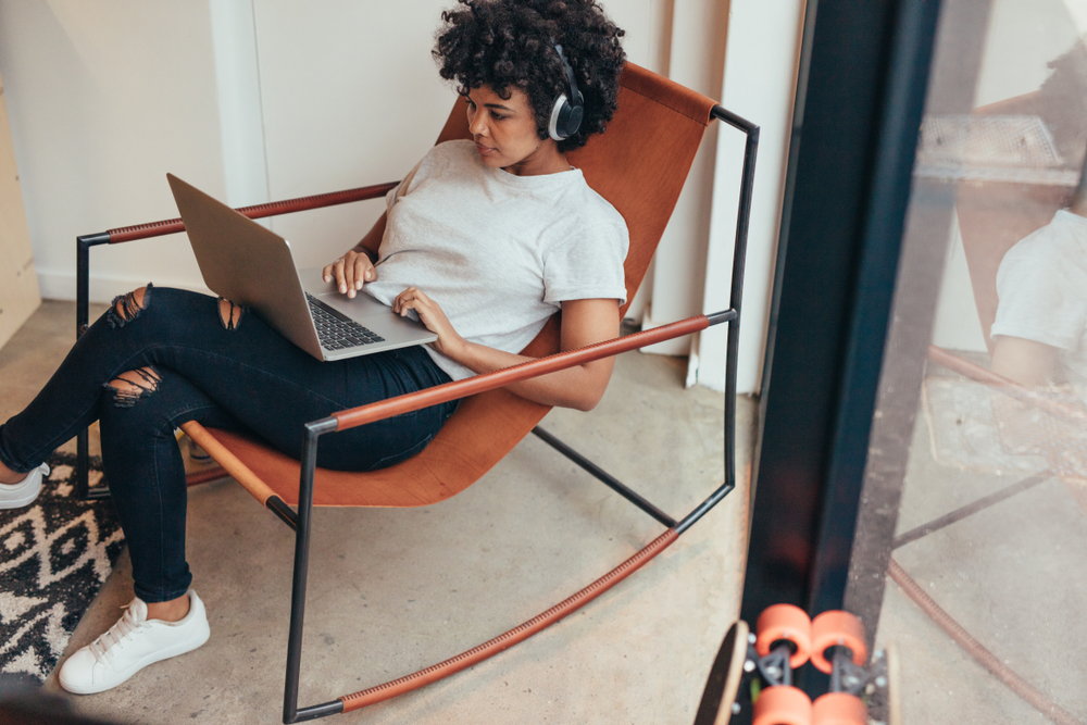 Young woman busy working on laptop at startup company. Female software engineer working on project and programming.