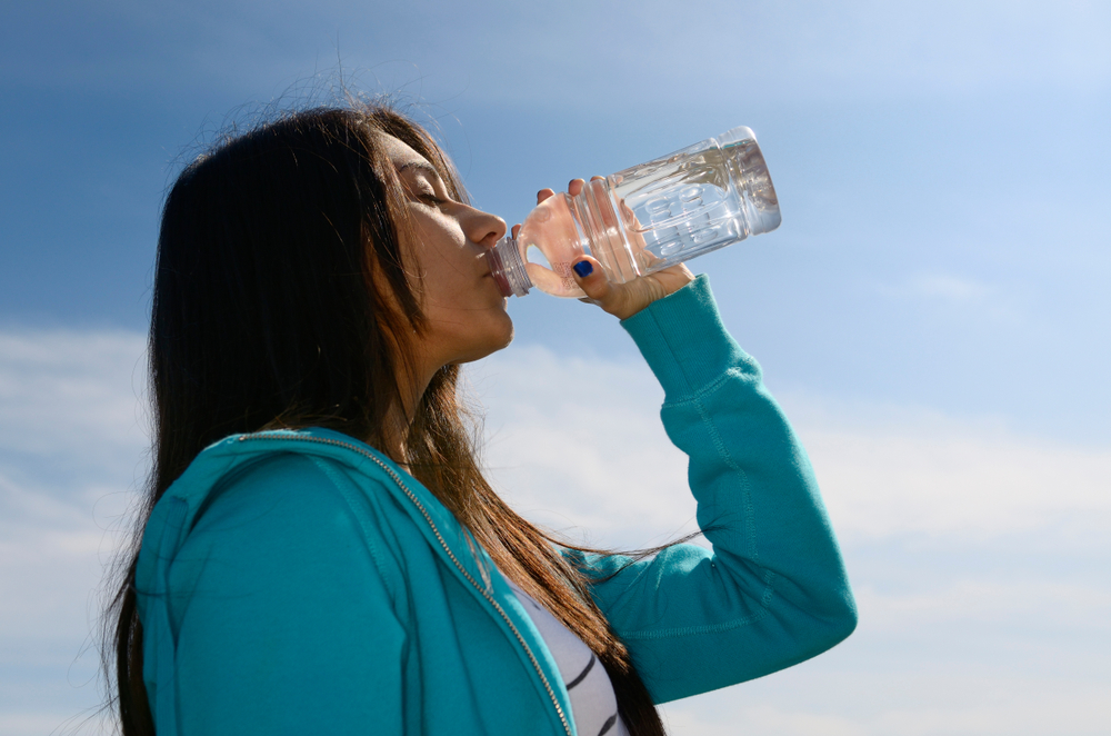 East Indian teenage girl with closed eyes drinking clear water after exercising Toronto, Ontario, Canada - April 30, 2011 with model release