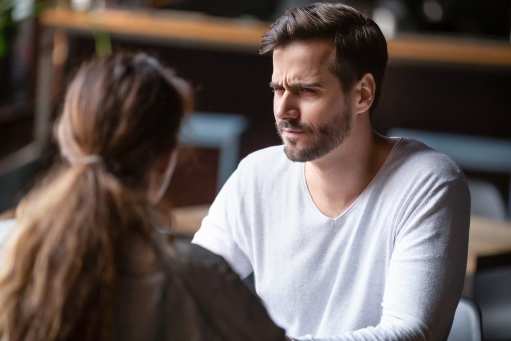 Doubting dissatisfied man looking at woman, bad first date concept, young couple sitting at table in cafe, talking, bad first impression, new acquaintance in public place, unpleasant conversation

