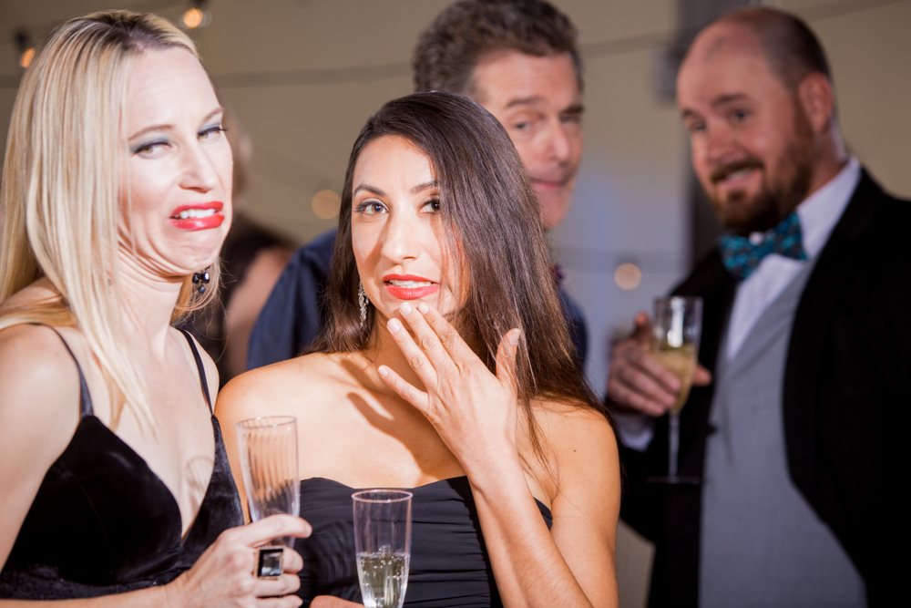 Two pretty women cringing over attention from men at party