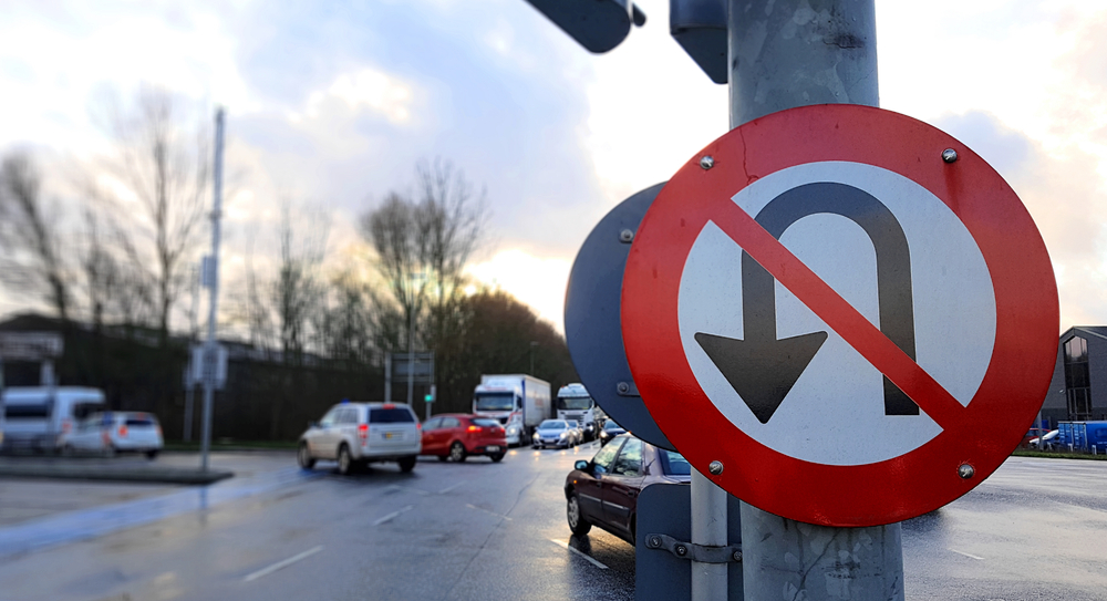 U turn prohibited sign in a traffic light with busy roads
