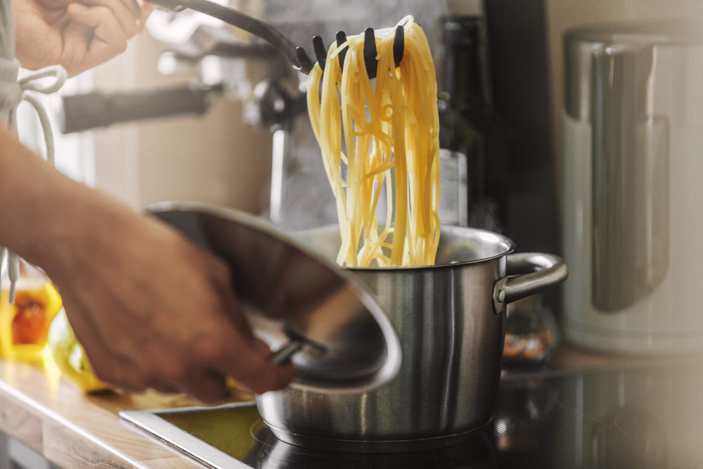 Man cooking pasta spaghetti at home in the kitchen. Home cooking or italian cooking concept.