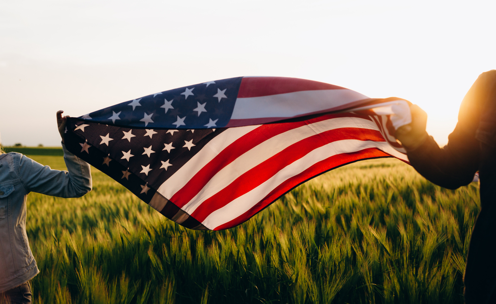 4th of july Patriotic holiday. Independence day. Hands holding american flag at sunse.