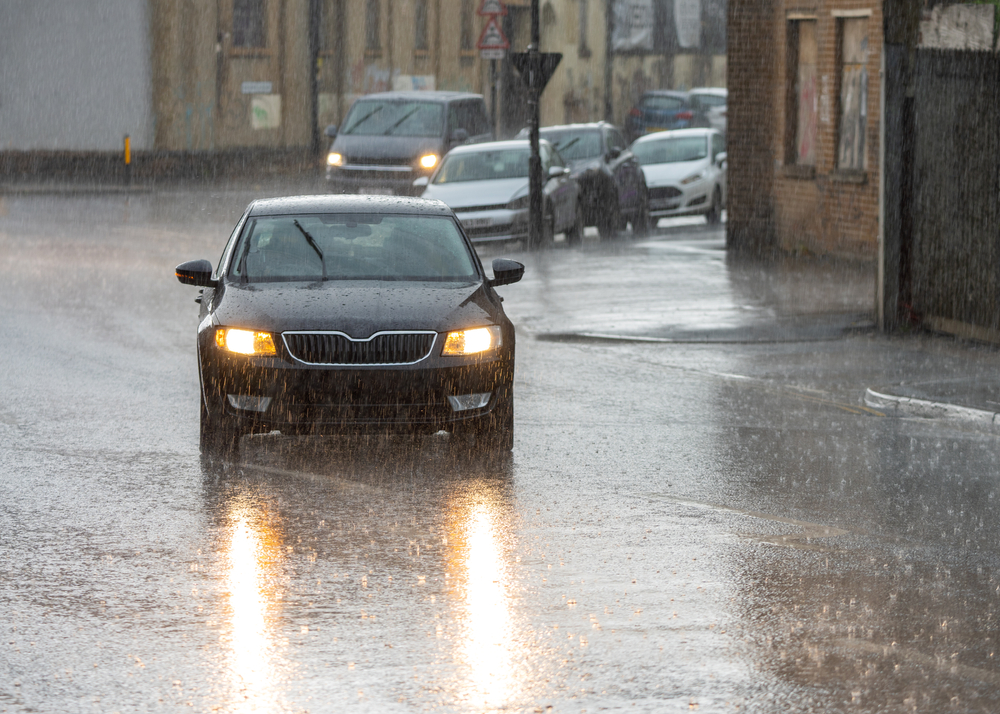 Heavy rain storm and flooded roads cars driving in downpour lights on reflecting in water of city streets. Flooding and risk of aquaplaning standing water on tarmac. Dark and moody torrential weather
