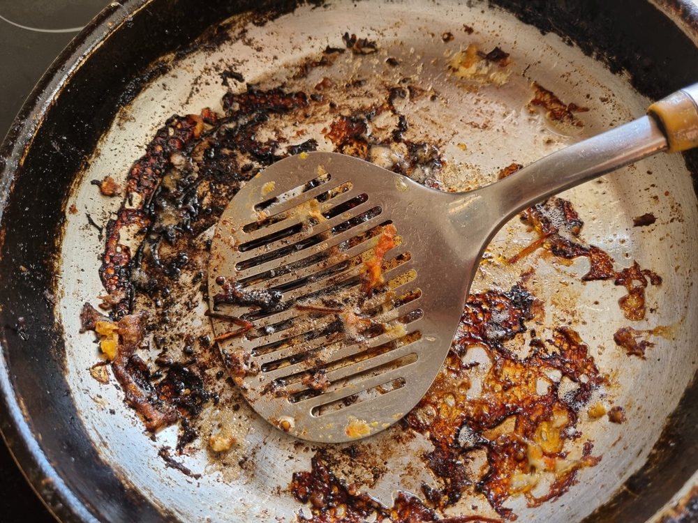 a frying pan with the remains of burnt scrambled eggs