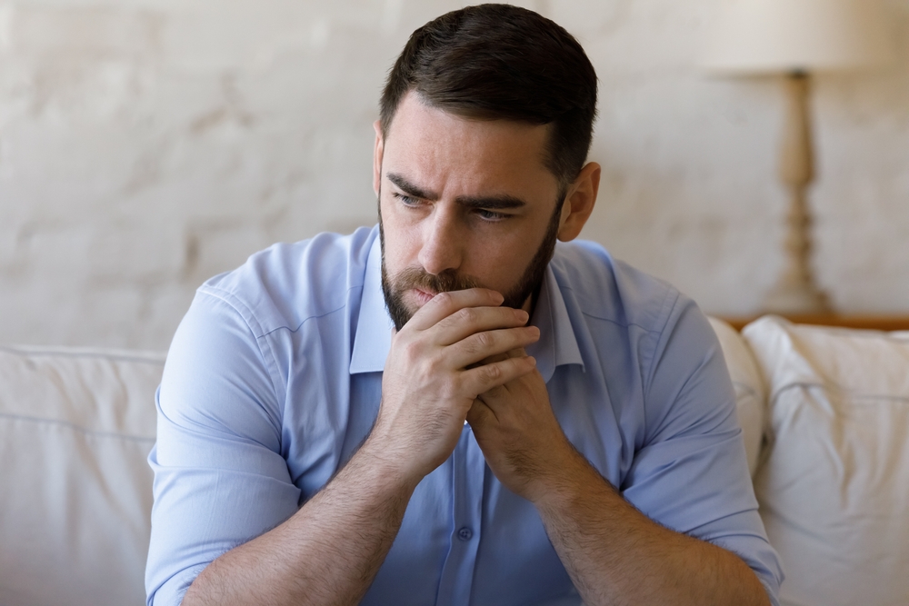 Worried concerned millennial business man thinking over bad news, problem solving, feeling stressed, depressed, frustrated, coping with nervous breakdown, emotional crisis. Negative emotions concept
