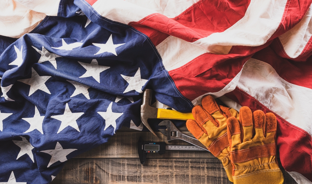 Happy Labor day concept. American flag with different construction tools on dark wooden background.