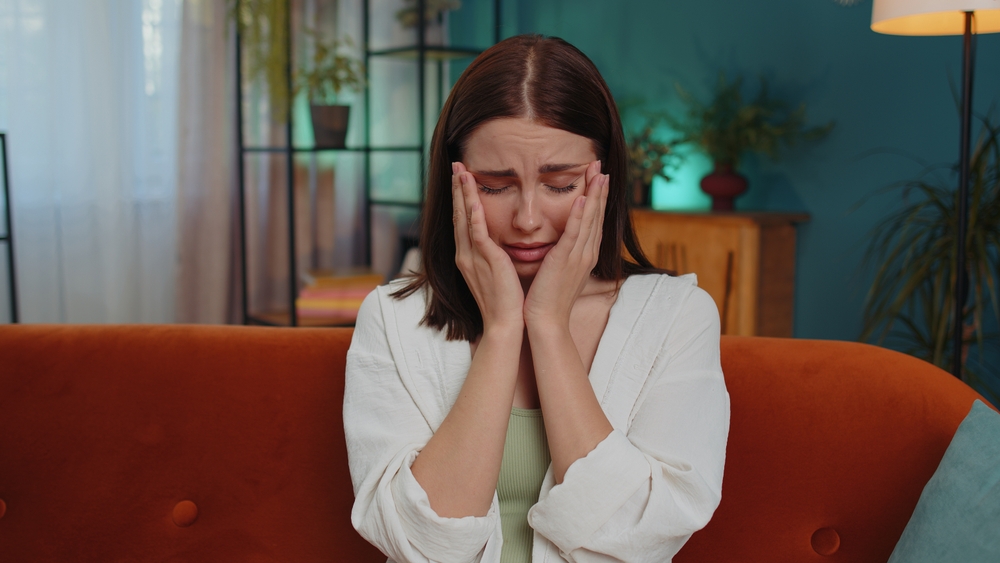 Upset disappointed caucasian young woman wipes tears and cries from despair, being sad because of unfair situation, unrequited love. Problem, break up, depressed feeling bad annoyed, burnout at home