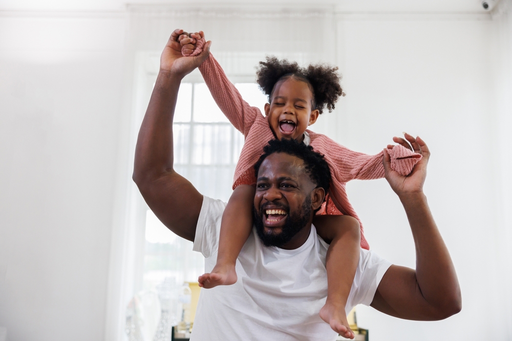 enjoy happy love black family african american father carrying daughter little african girl child smiling in the white living room at home. Happy black African American father day concept.