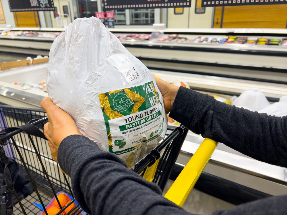 Sacramento, CA, USA November 11, 2022 Customer holding a Frozen Keller brand organic ranch raised whole turkey for sale in a freezer at a local supermarket
