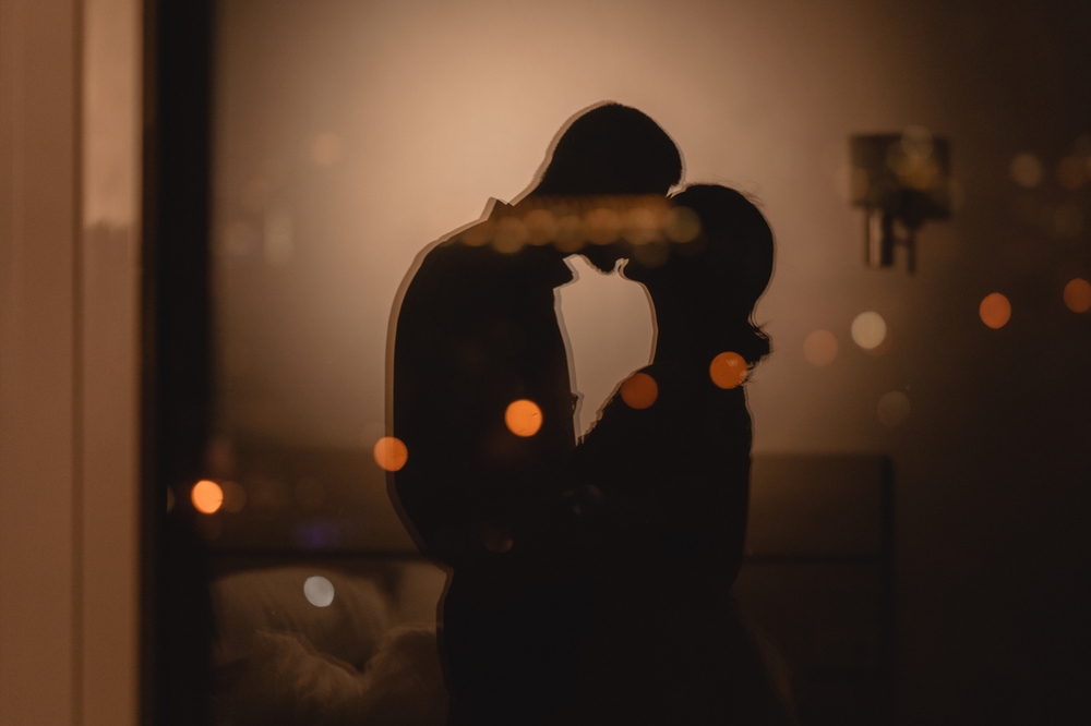 Reflection in the window couple in love kissing with lights in the background, romantic night in the hotel concept