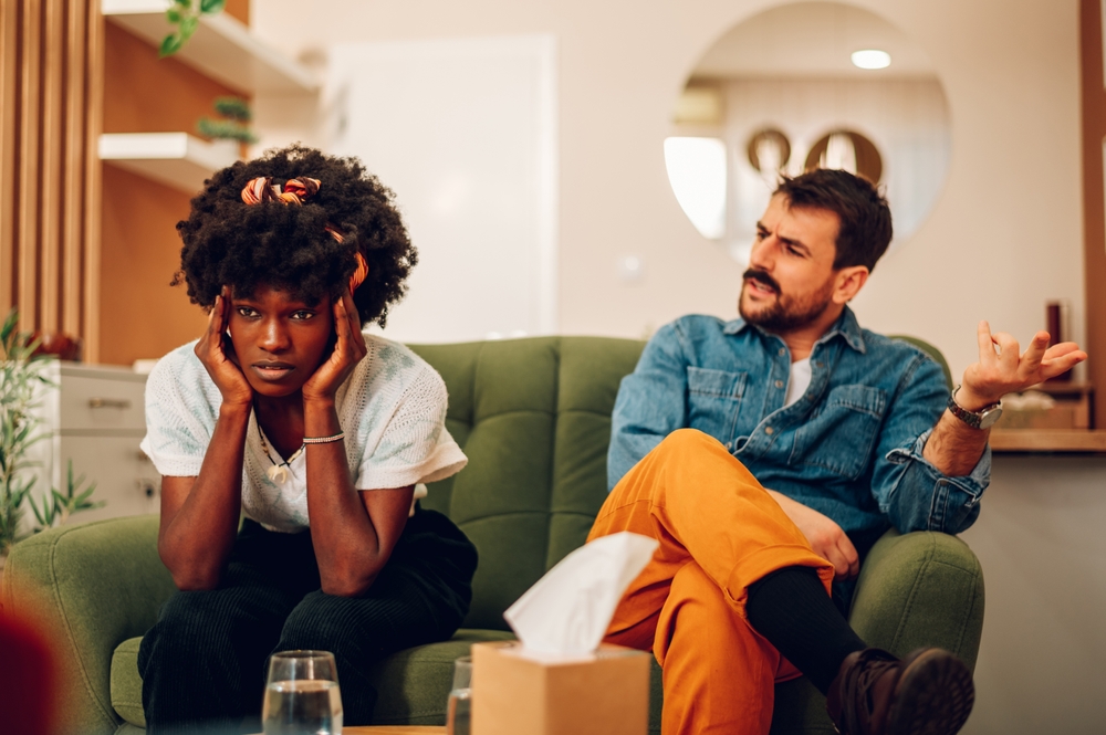 Biracial couple argue in therapy. Diverse spouses marriage counseling. Custody battle, divorce, adoption, alimony or family problem. Focus on a african american woman having a headache. Copy space.
