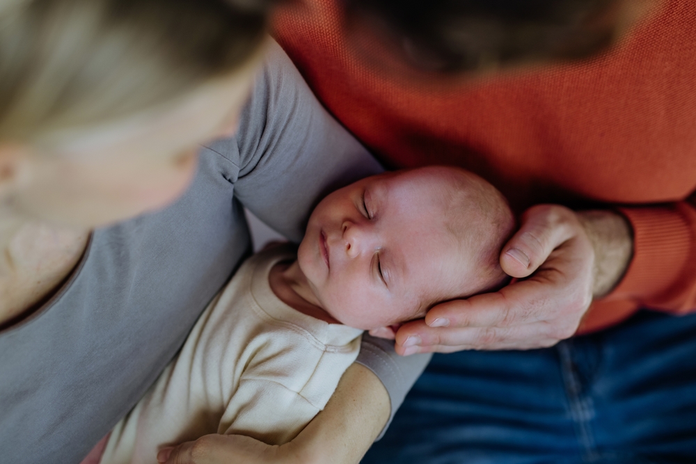 Close-up of parents cuddling their newborn baby.