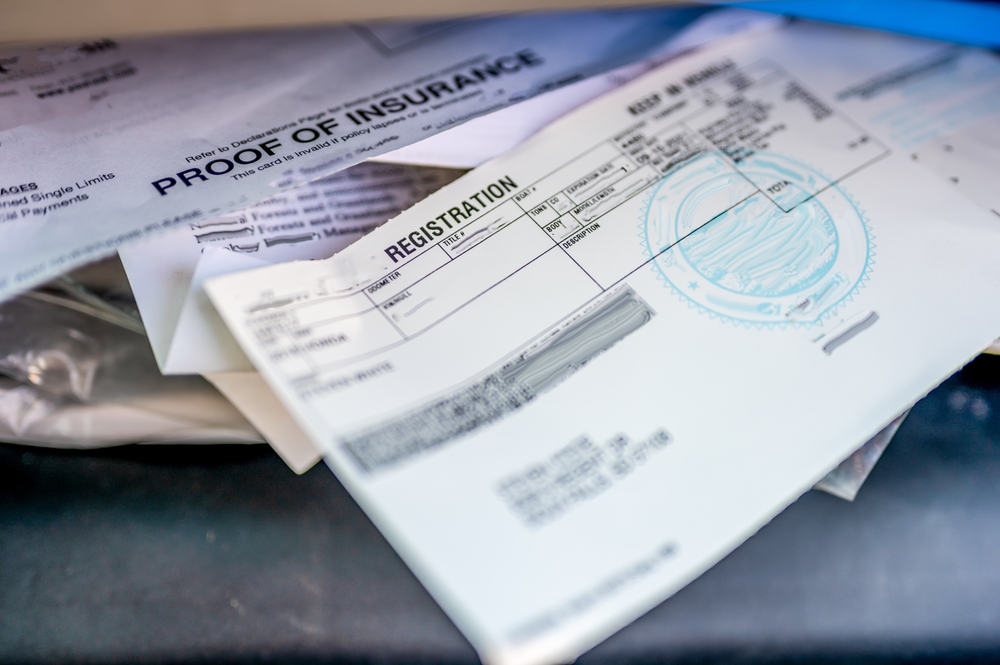 Proof of insurance and vehicle registration documents in the glove compartment of a car.
