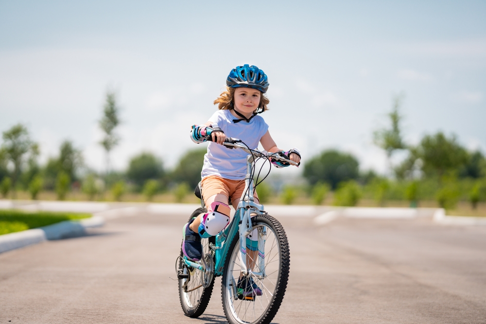 Child in safety helmet riding bike. Boy riding bike wearing a helmet outside. Child in safety helmet riding bike. Little kid boy learns to ride a bike. Kid on bicycle. Happy child in helmet riding a
