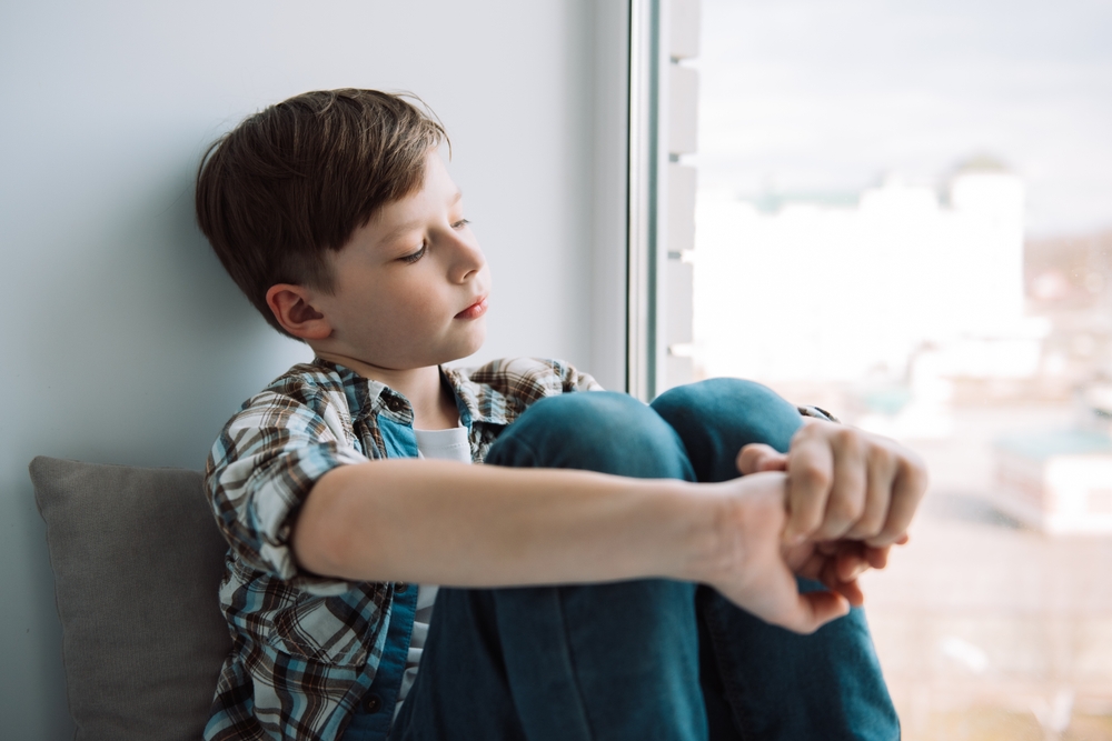 Lonely sad boy at home. The concept of loneliness. saddened alarmed child alone at home