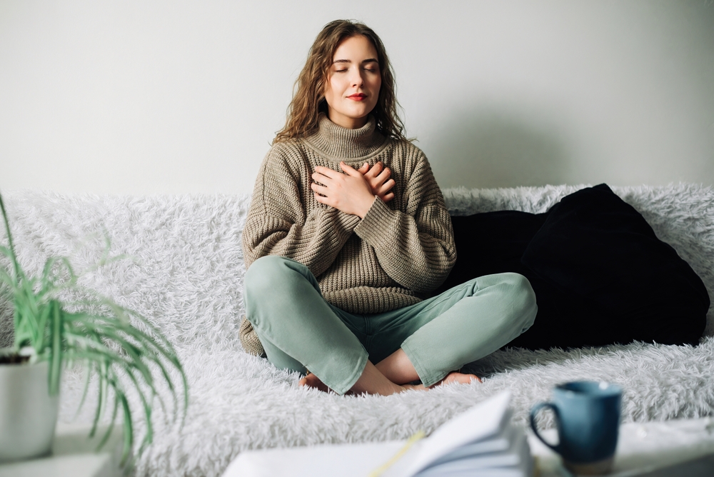 Relaxation techniques: Woman practicing pranayama in lotus position on bed, breathing exercises to reduce stress and anxiety, achieving inner balance and harmony, mindfulness and meditation practice
