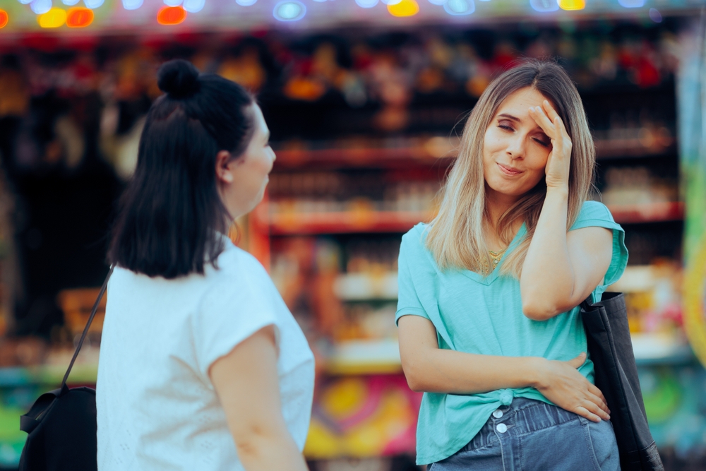 Woman Having a Headache After Talking to a Friend. Bored girl meeting an annoying person listening to her chit chat

