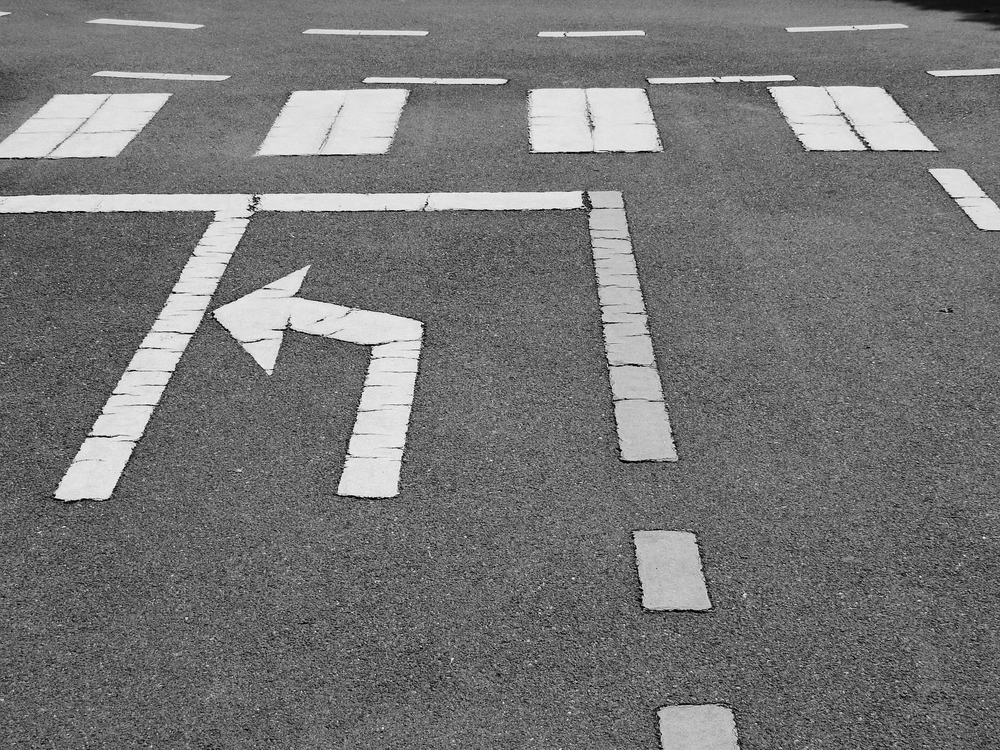 white arrow symbol with white lines on asphalt road texture
