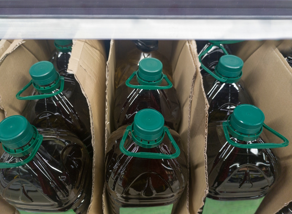 Extra virgin olive oil bottled and displayed on cardboard box at supermarket shelve. Overhead view
