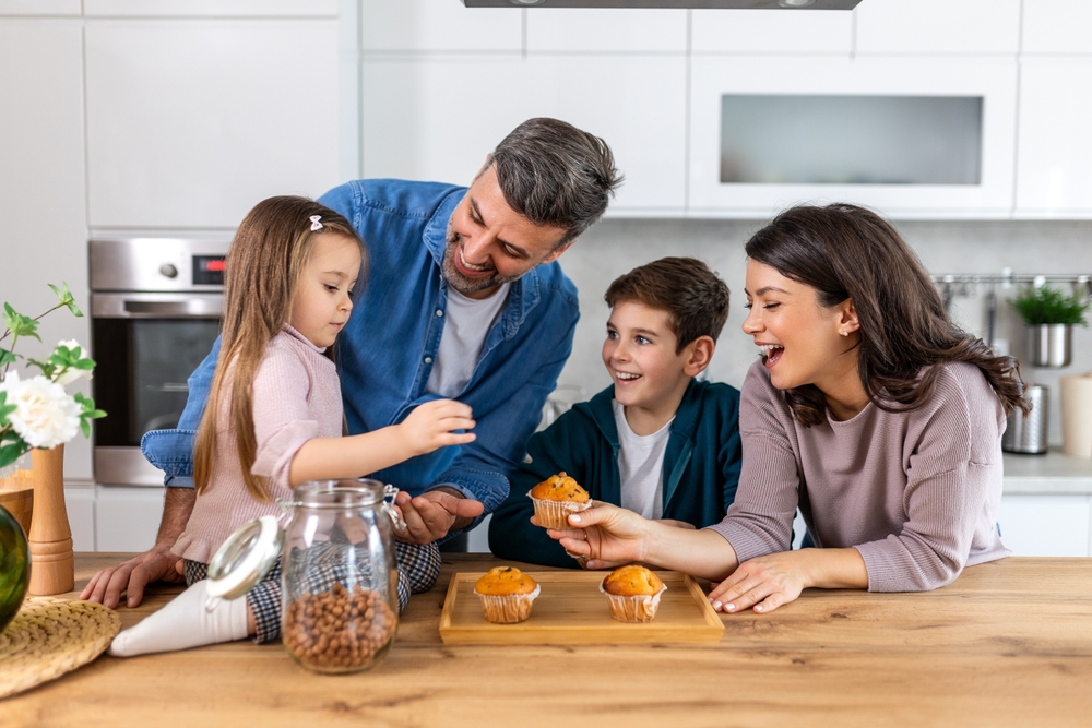 In the kitchen, a family enjoys cupcakes together, sharing smiles and laughter as they indulge in the sweet treats.