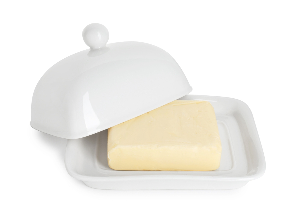 Dish with block of tasty butter isolated on white
