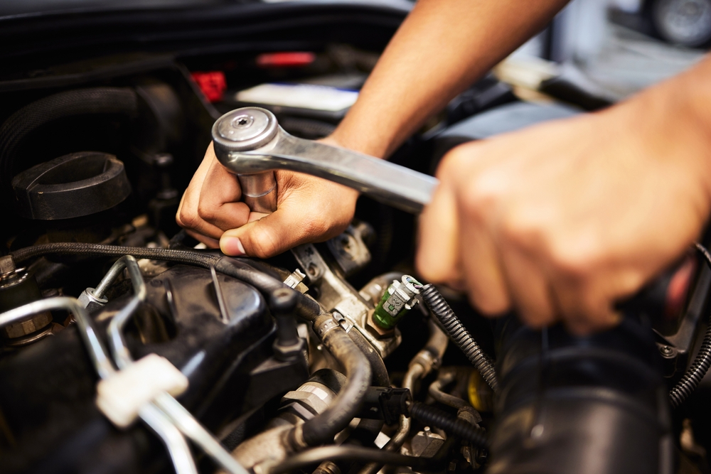Person, hands and mechanic with spanner for fixing engine and motor maintenance in workshop. Industry, engineer and vehicle repairs with oil change in routine car checkup and service in garage
