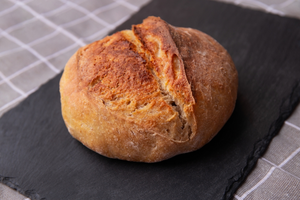 Sourdough Bread. A Beautiful Round Loaf on a Black Stone Board. Cooking Healthy Sourdough Bread at Home
