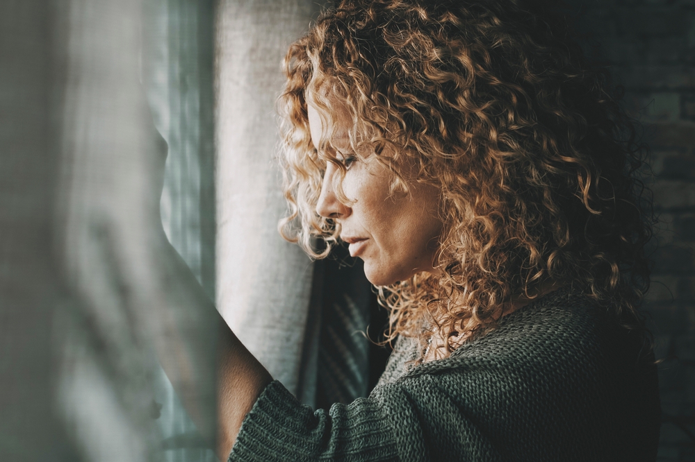 Sadness worried woman inside home near the window. Bad unhappy day. Side view of female people sad with depression. Problems and home domestic loneliness. House couple violence. Wife alone in trouble