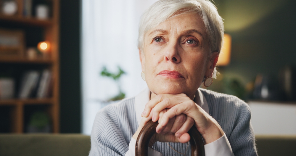Walking stick, memory and senior woman in home with thinking, remember or nostalgia for past. Dreaming, medical support and elderly female person with cane for dementia disease in retirement facility
