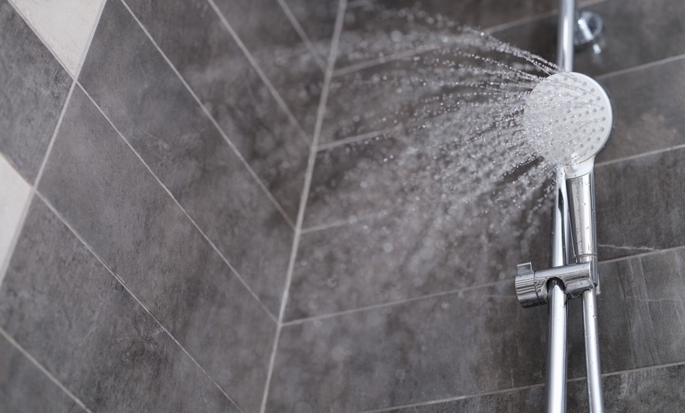 Water is pouring from the shower head into the shower room, close-up. Refreshing shower, cleanliness and hygiene
