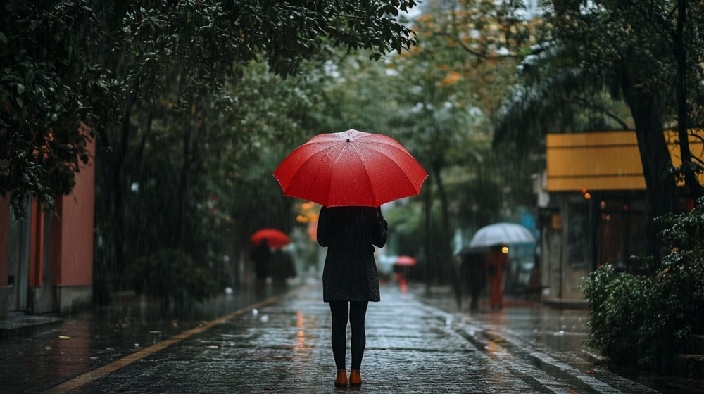 Woman with red umbrella standing in the middle of the street on a rainy day