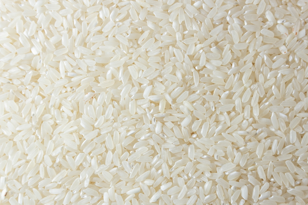 Dry Uncooked White Rice Background - Top View, Flat Lay. Scattered Raw Long Grain Rice. Asian Cuisine and Culture. Healthy Eating Ingredients. Diet Food
