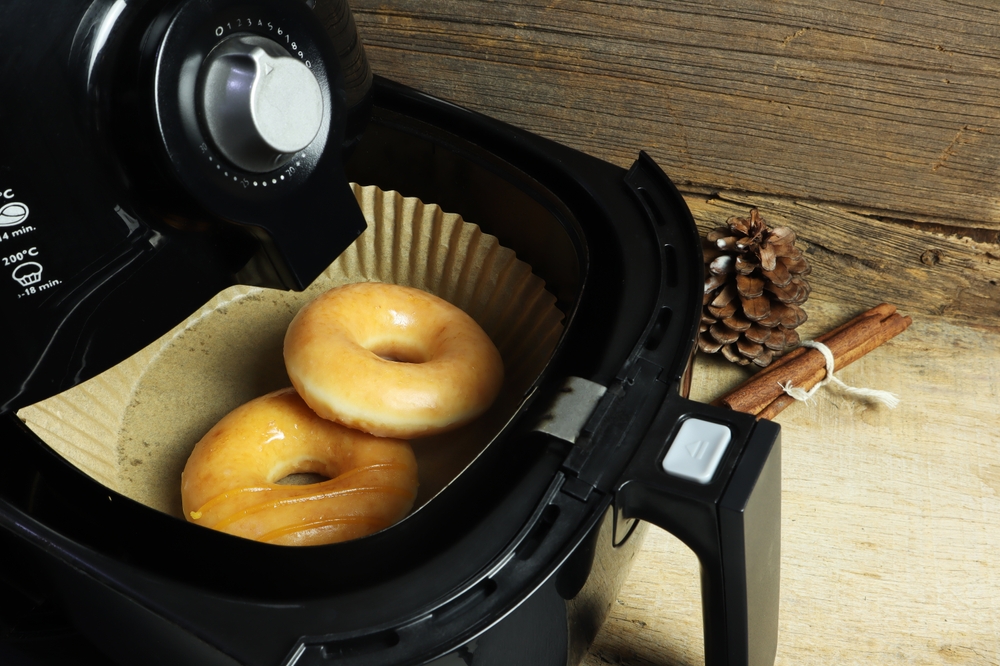 homemade organic wheat grain doughnut or donut are baked by using a black air fryer or oil free fryer appliance for being food in the Christmas party with background of old wooden table