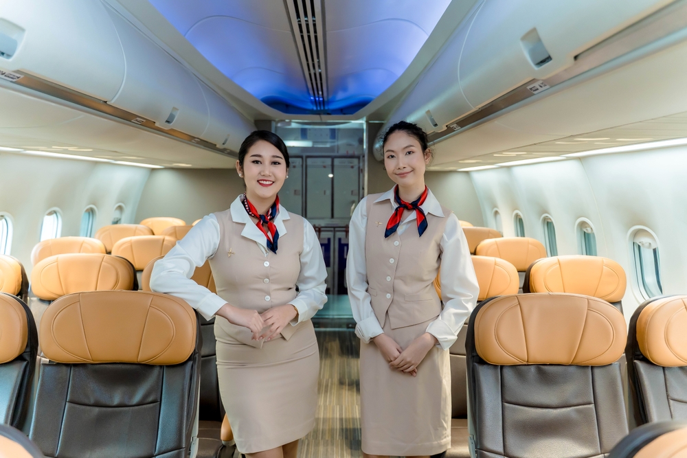 Smiling flight attendants standing in airplane cabin aisle, ready to assist passengers with in-flight services and ensure a safe and pleasant journey
