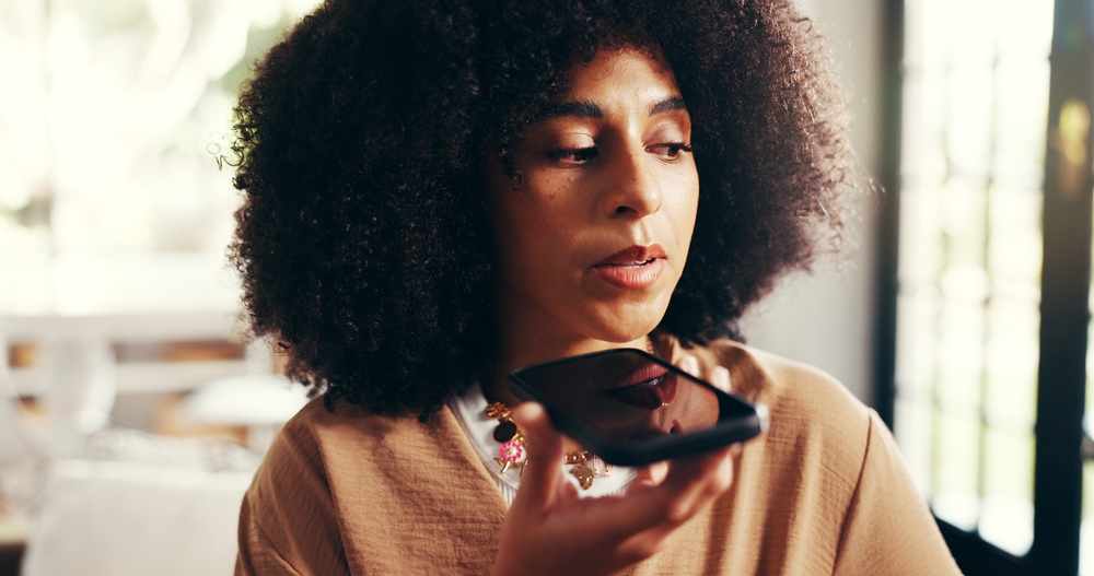 Woman, talking and speaker with phone call in home for communication, conversation and discussion. African person, user and recording with mobile for voice note, chat and audio message in house
