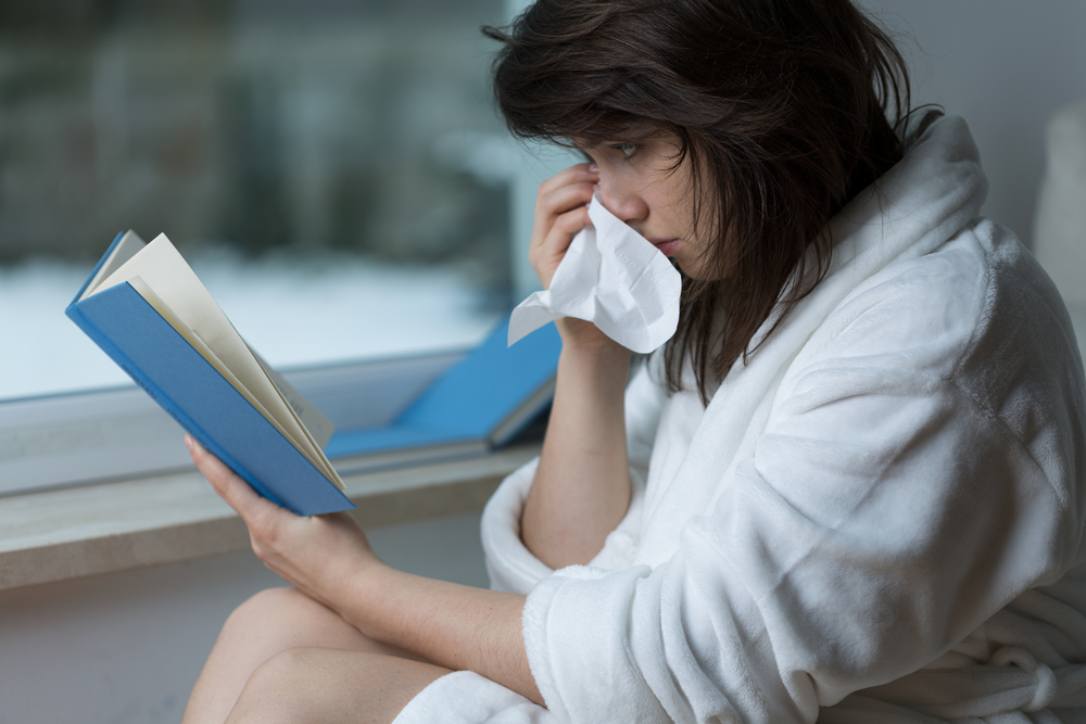 Sensitive young woman reading romance and crying