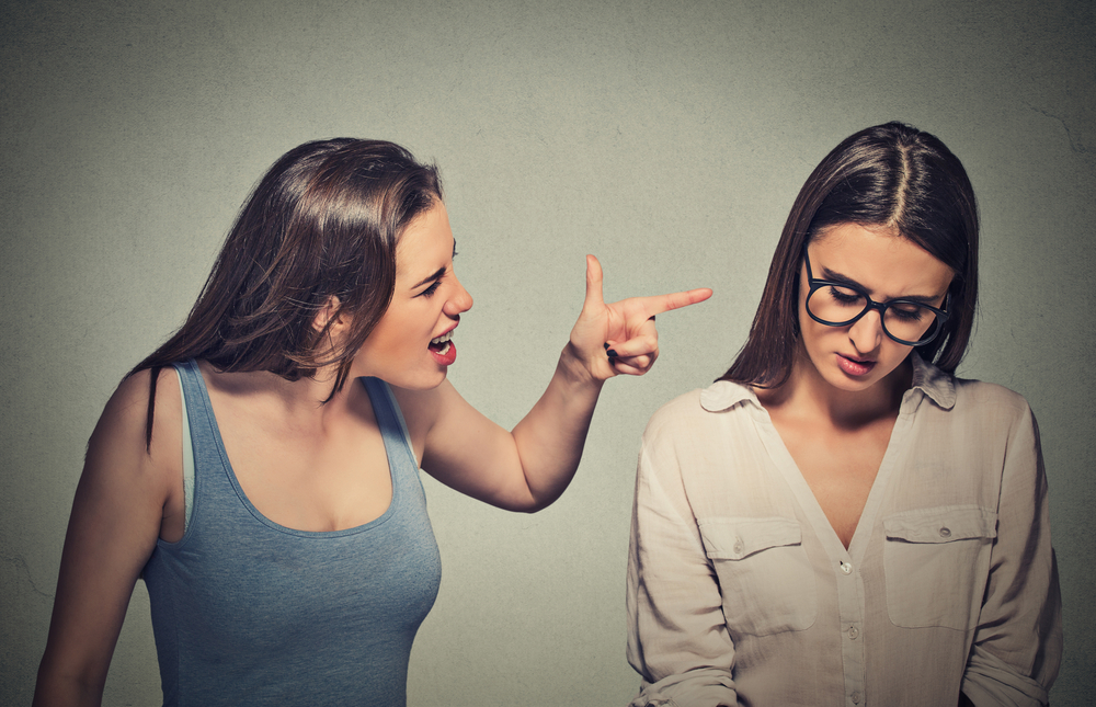 Bullying, friendship and people concept. Girl patronizing screaming pointing finger at shy timid nerdy woman who is looking down
