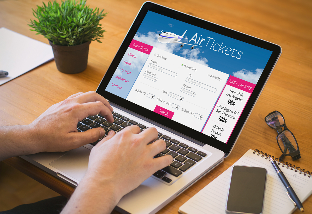 Close-up top view of man working on laptop with tickets flights web. all screen graphics are made up.
